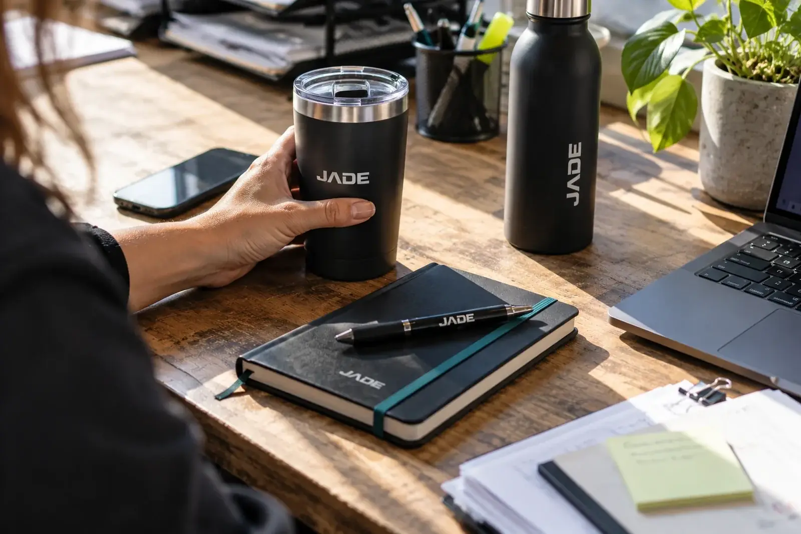 Tasse, bouteille, carnet et stylo au logo JADE sur un bureau