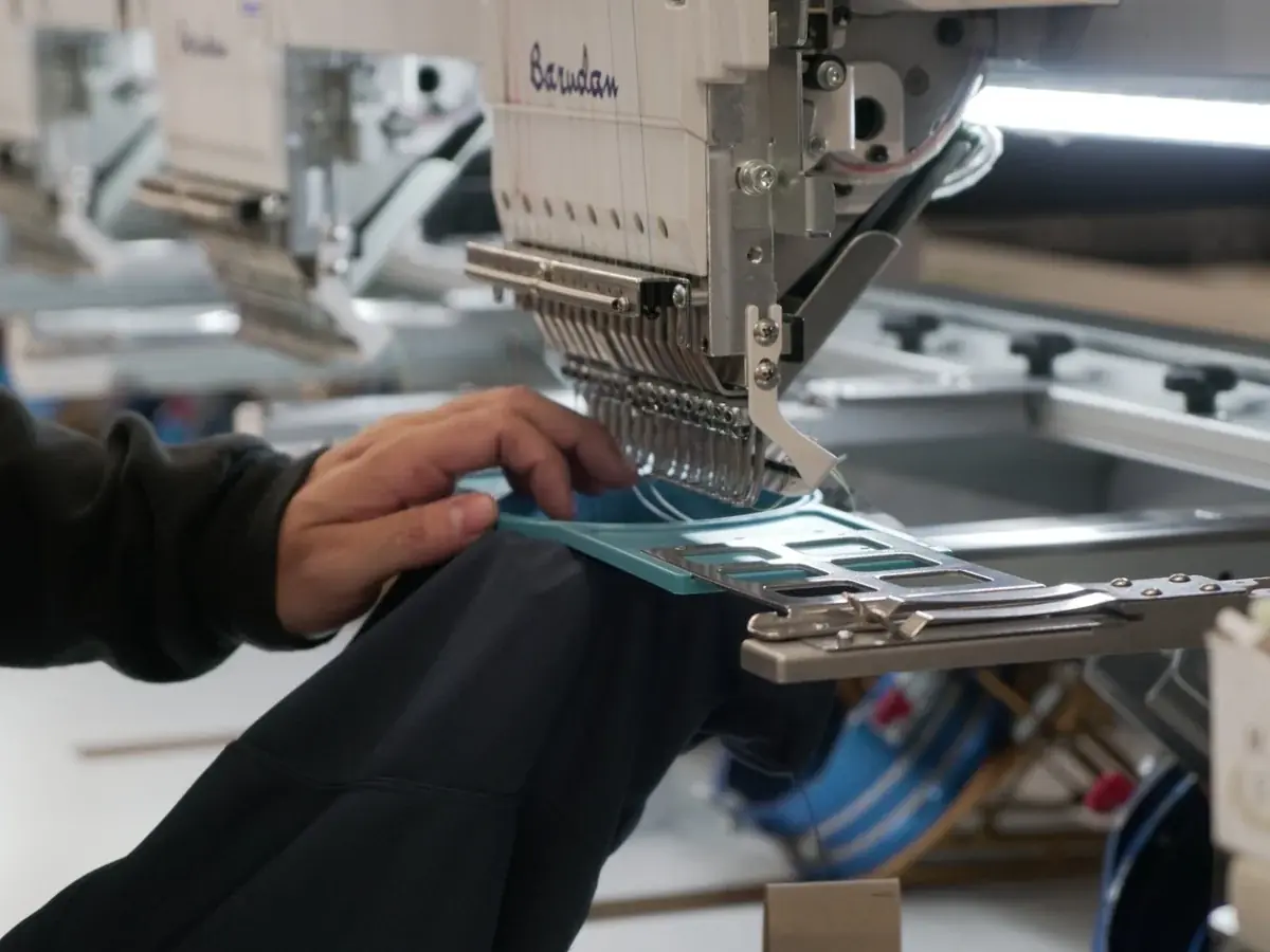 Machine à broder Barudan en train de poser un logo sur un vêtement